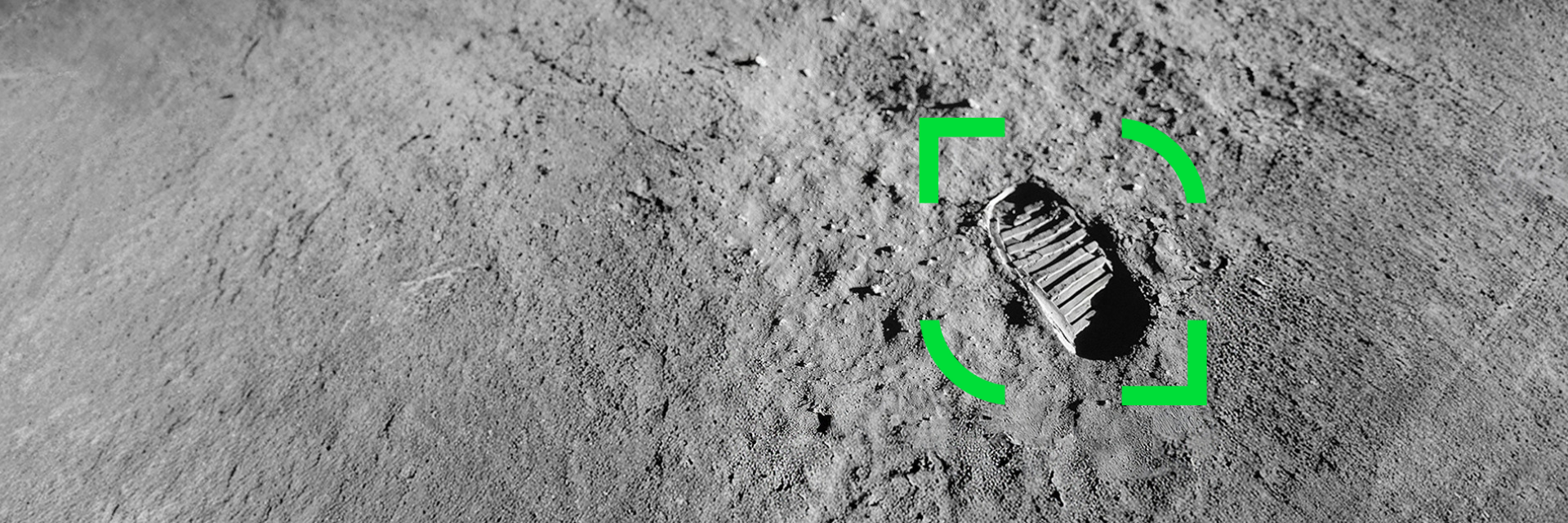 Fotavtrykk på måneoverflaten, omgitt av en grønn markeringsramme som indikerer fokuspunkt. Grå, støvete terreng dekker bakgrunnen.